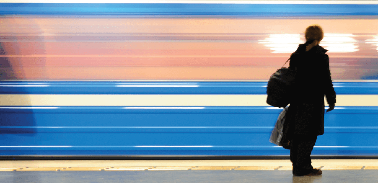 Silhouet van vrouw op perron terwijl een trein achter haar voorbij raast